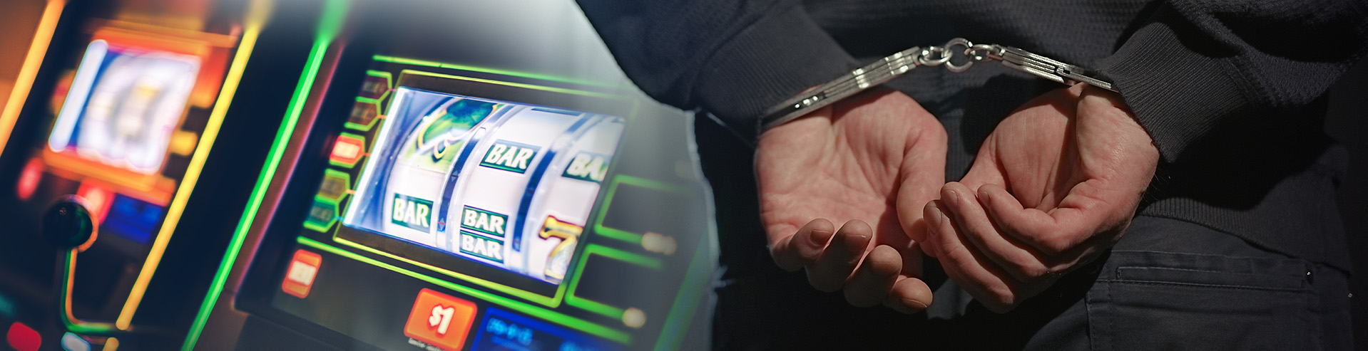A handcuffed man in front of a slot machine